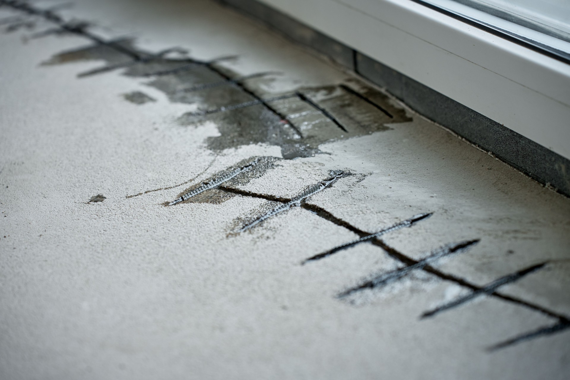 Repairing cracks in concrete floor near window using sealant